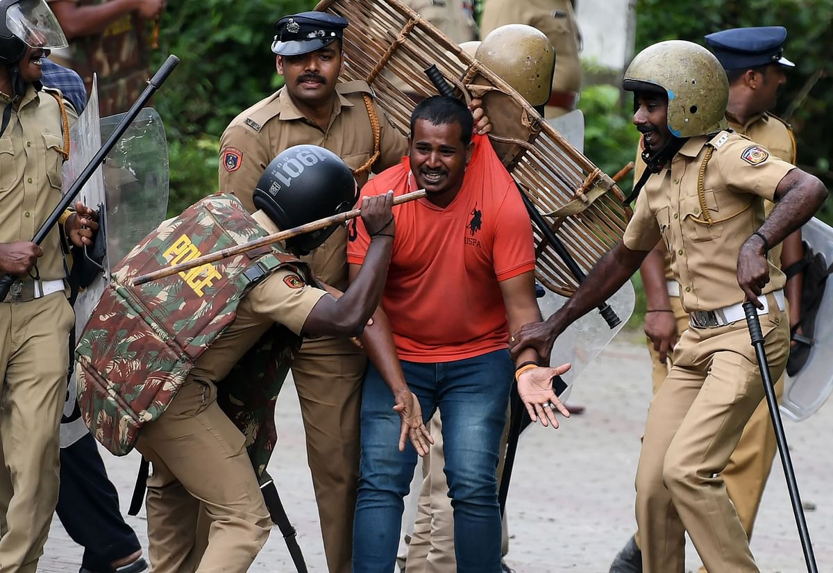 Indian police beat a Hindu activist as he pleads for his own safety as protesters rallied against a Supreme Court verdict revoking a ban on women`s entry to a Hindu temple, in Nilackal in southern Kerala state on 17 October 2018. Photo: AFP