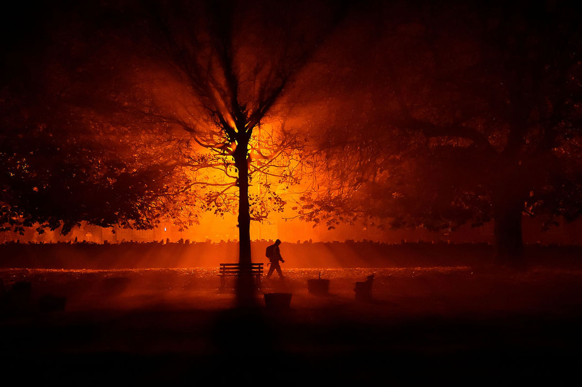 A man uses a torch to walk through a park during cold fog at night in Athboy, Ireland, October 31, 2018. Picture taken 31 October 2018. Photo: AFP