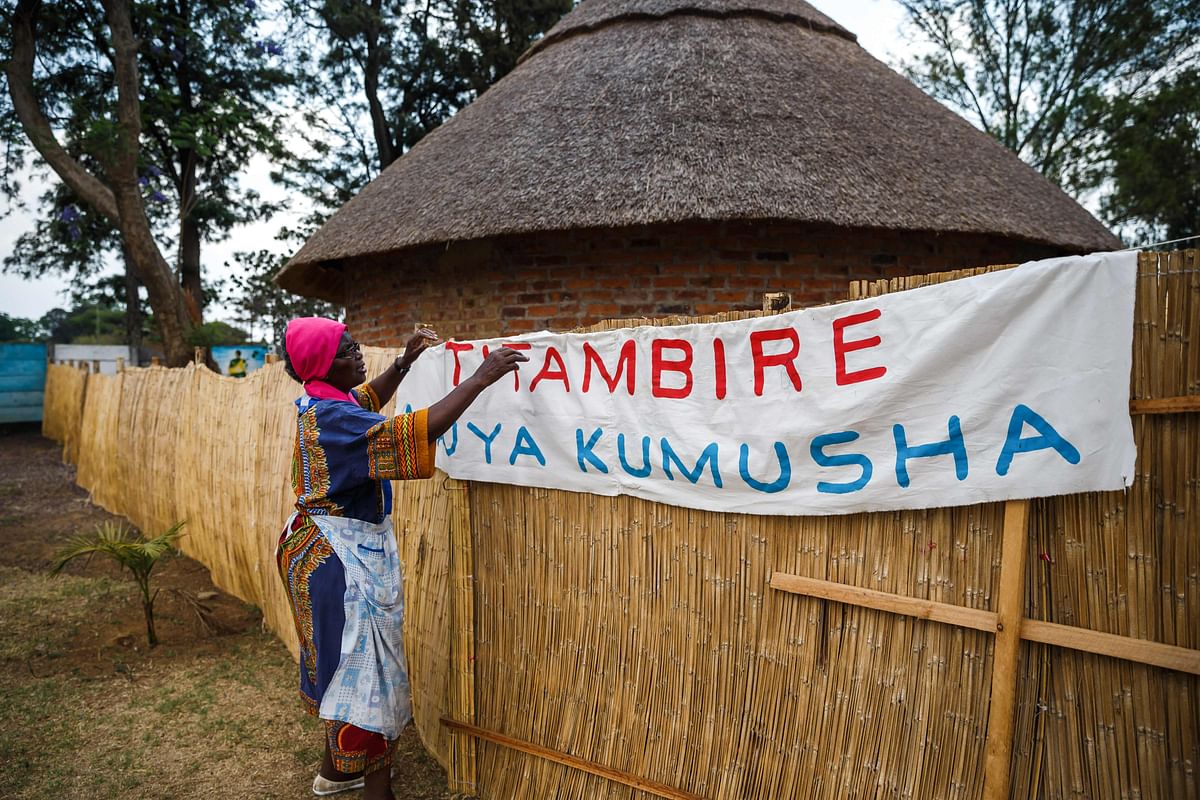 Poet, storyteller and retired schoolteacher, Hatifari Munongi adjusts a welcome banner reading at the replica traditional homestead she set up in the backyard of her house in the suburb of Marlborough in Harare on 18 October 2018. Photo: AFP