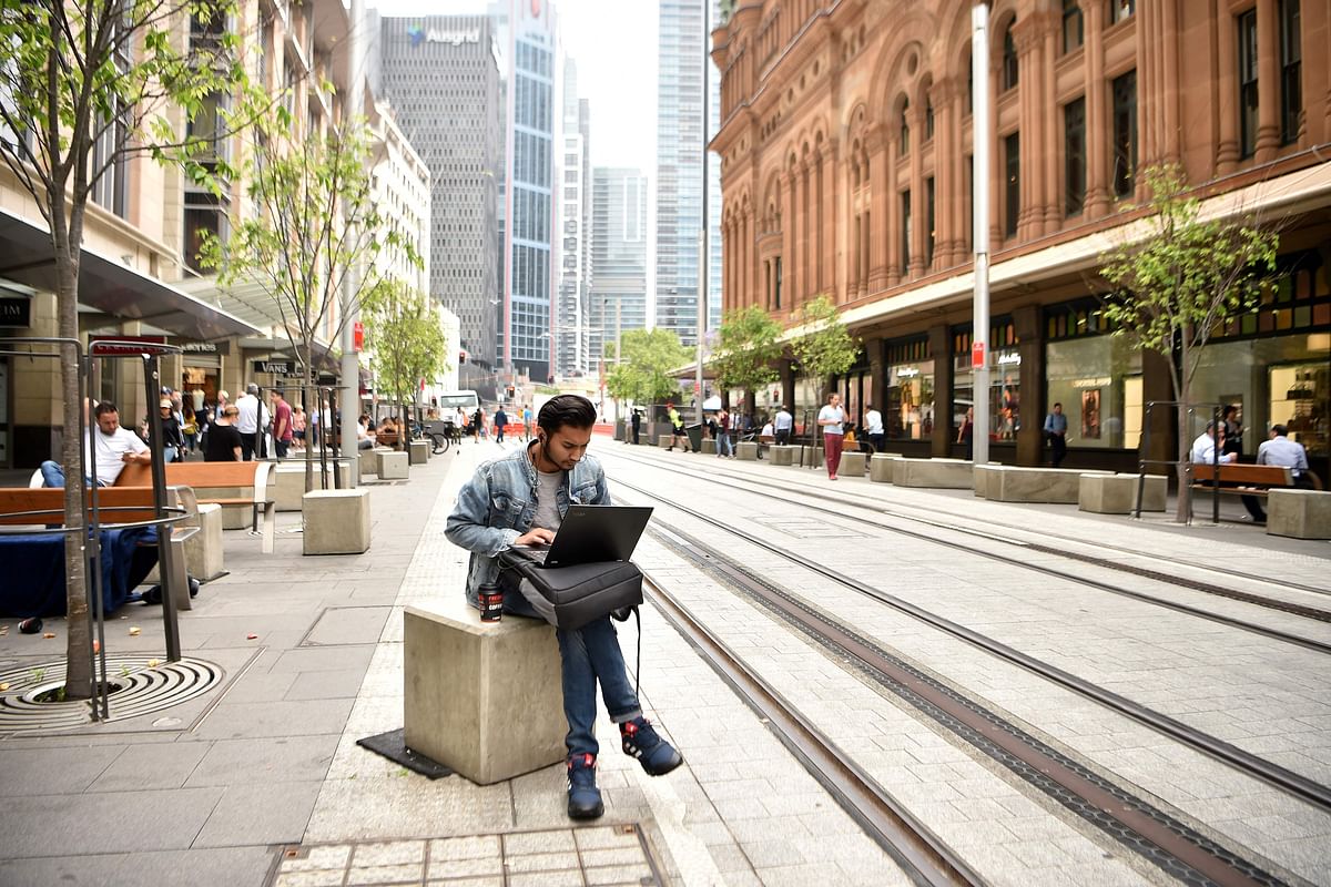 This photo taken on 5 November 2018 shows a man using a laptop computer on a street in the central business district of Sydney. Australia`s central bank meets to set interest rates on 6 November as warning lights begin to blink in the country`s record-beating economy. Photo: AFP