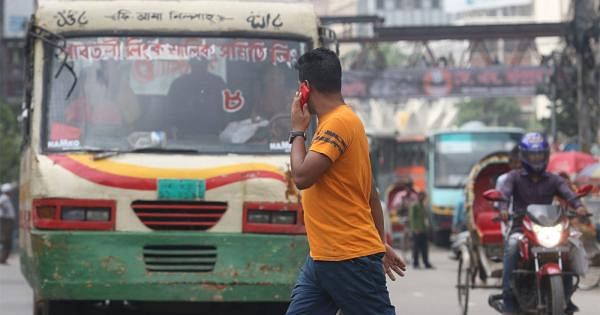 A man crosses road in front of a moving bus while talking in mobile phone. Prothom Alo File Photo