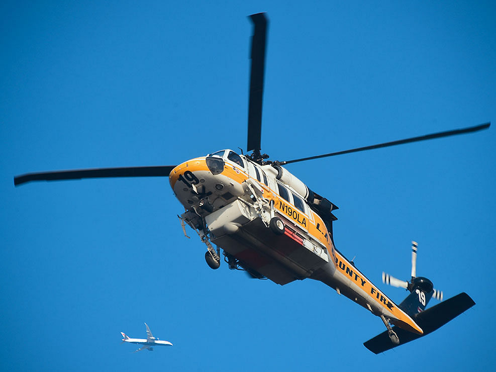 An aircraft flies past a helicopter going down to collect water at Pepperdine University in Malibu, California, on 11 November 2018, as the battle to control the Woolsey Fire continues. Near Los Angeles, where the `Woolsey Fire` is threatening mansions and mobile homes alike in the coastal celebrity redoubt of Malibu, the death toll has been limited to two victims found in a vehicle on a private driveway. Photo: AFP