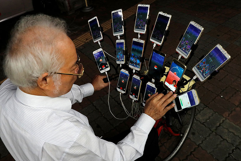 Taiwanese Chen San-yuan, known as `Pokemon grandpa`, plays the mobile game `Pokemon Go` by Nintendo, near his home with 15 mobile phones, in New Taipei City. Photo: Reuters