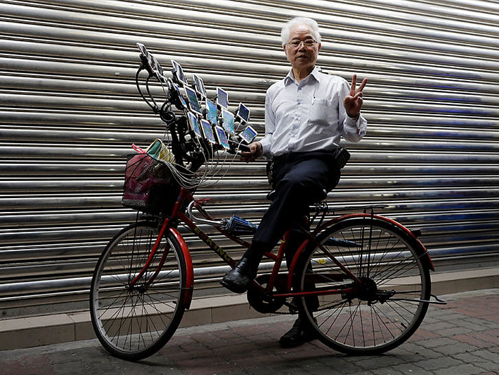 Taiwanese Chen San-yuan, 70, known as `Pokemon grandpa`, poses with his bicycle as he plays the mobile game `Pokemon Go` by Nintendo, near his home with 15 mobile phones, in New Taipei City. Photo: Reuters