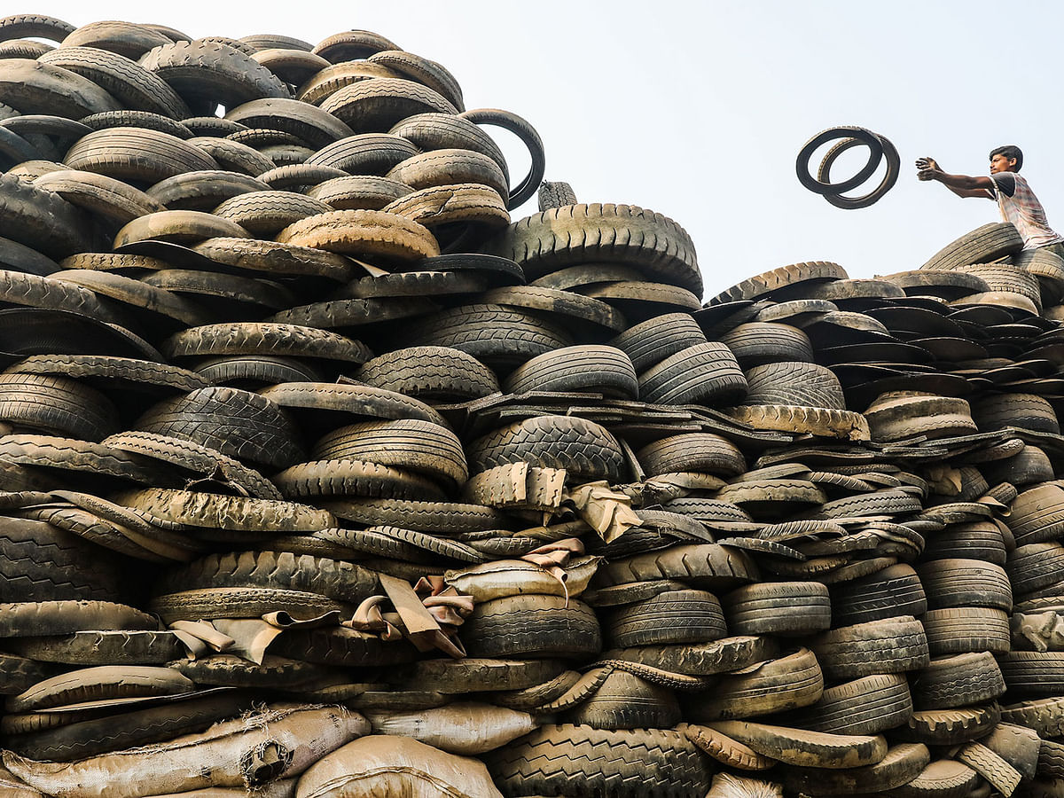 A worker busy sorting out tires from a dump in Mohammadpur Beribandh area of Dhaka on 20 November. The dumped tires, collected from the city`s car servicing outlets, sell at Tk 15 to 18 per Kg and are used as brick factory fuel and road construction material. Photo: Dipu Malakar
