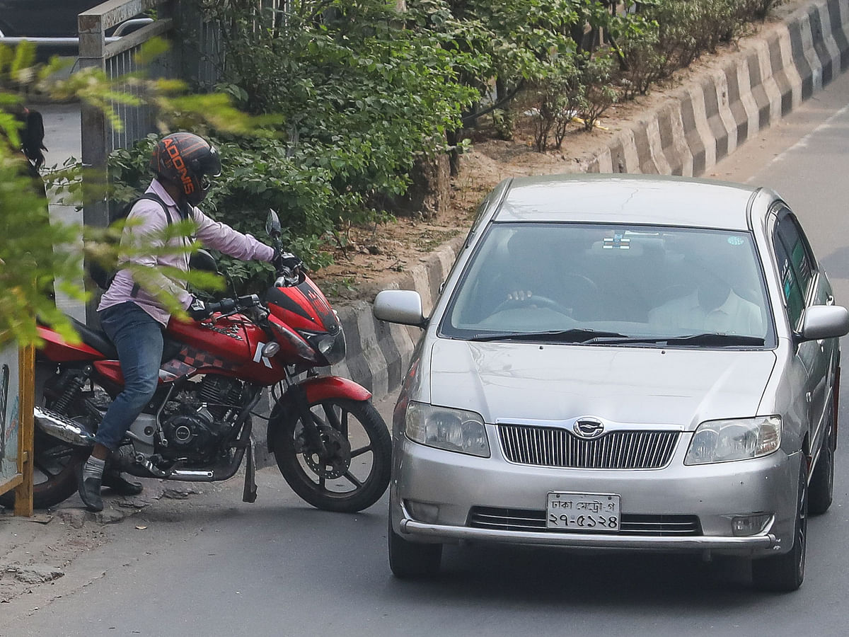 A motorcyclist changing lane at Sat Masjid Road in Dhaka through the narrow space of a road divider taking risks on 20 November. Photo: Dipu Malakar