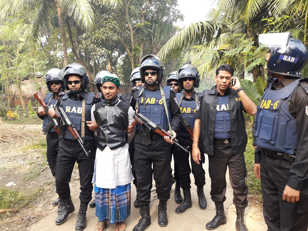 A team of Rapid Action Battalion is seen with Akhter Hossain detained from his father’s residence at Kaluhati, Jhenaidah on 21 November for his alleged involvement with militancy. Photo: Azad Rahman