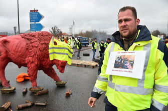 A Yellow vest (Gilet jaune) protestor holds a picture of the French president and his wife posing with dancers and reading `Village people in concert at the Elysee Palace` as they block an access to the A11 and A 28 highways in Saint Saturnin, near Le Mans, northwestern France, in the night of 24 November 2018 to protest against rising oil prices and living costs. Police fired tear gas and water cannon on 24 November in central Paris against `yellow vest` protesters demanding French president roll back tax hikes on motor fuel. Photo: AFP