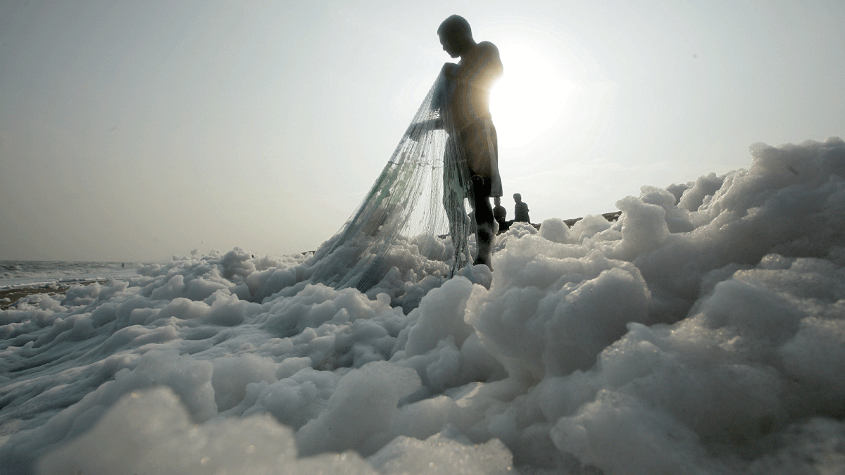 A fisherman pulls his net on the shore filled with foam at the Marina beach in Chennai, India, 23 November 2018. Photo: Reuters