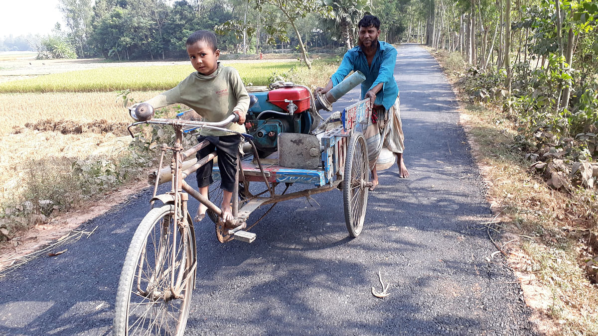 A three-year old holding handle of a rickshaw van while the father pushes it from behind. Chandaikona, Raiganj, Sirajganj on 24 November. Photo: Sajedul Alam