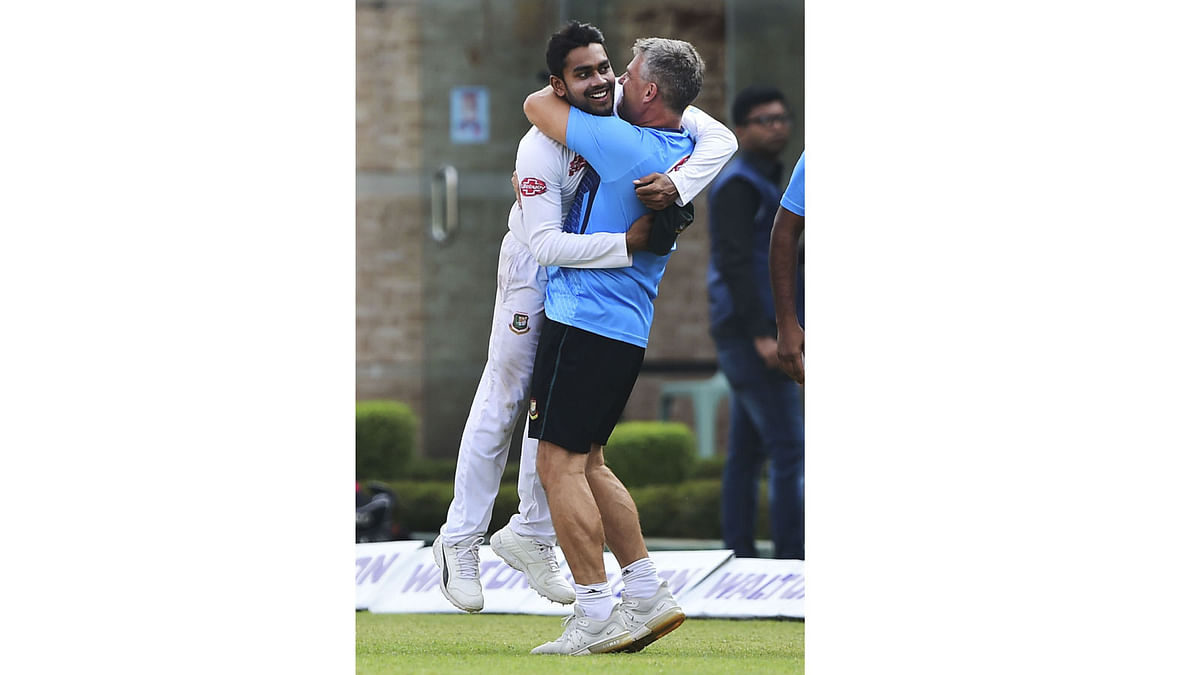 Bangladesh`s cricket coach Steve Rhodes (R) hugs all-rounder Mehidy Hasan (L) as they celebrate their victory after beating visiting West Indies in the two-match Test series at the Sher-e-Bangla National Cricket Stadium in Dhaka on 2 December 2018. Photo: AFP