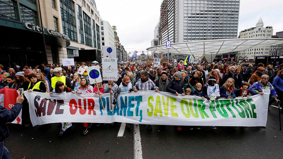 People hold a banner reading `Save our planet, save our future` during the `Claim the Climate` march to raise awareness for climate change, in Brussels on 2 December 2018 . Photo: AFP