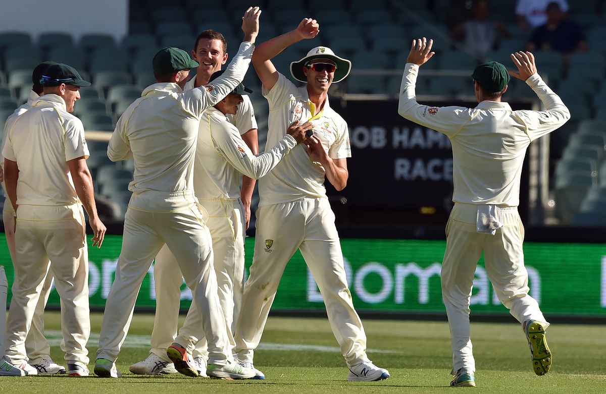 Australian fieldsman Pat Cummins (C) is congratulated by teammates for the run out of India`s batsman Cheteshwar Pujara with a direct throw during day one of the first cricket Test match at the Adelaide Oval on 6 December 2018. Photo: AFP