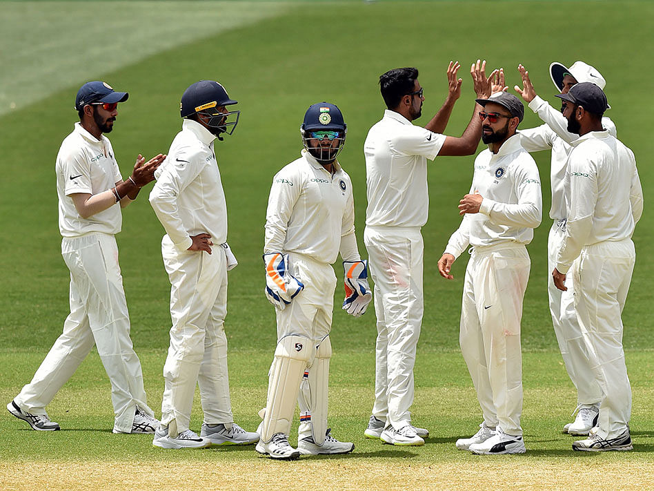 India`s bowler Ravichandran Ashwin (C) celebrates with teammates after dismissing Australia`s batsman Shaun Marsh during day two of the first Test match at the Adelaide Oval on 7 December 2018. Photo: AFP