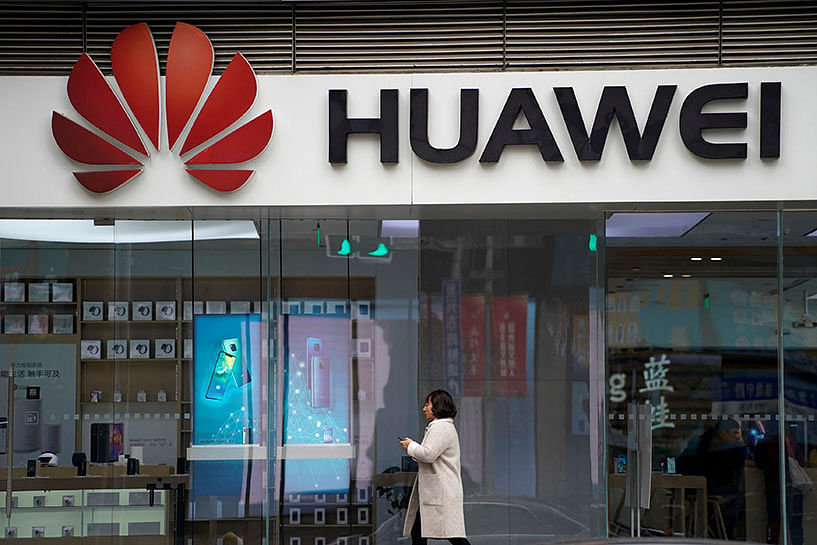 A woman walks by a Huawei logo at a shopping mall in Shanghai, China on 6 December. Photo: Reuters