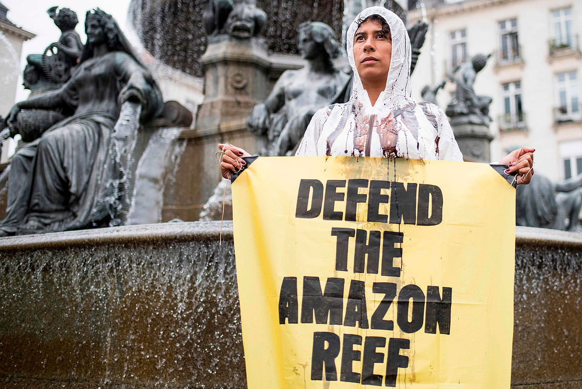 In this file photo taken on 22 September 2018 a Greenpeace activist stands in a fountain with a sign which reads `Defend the Amazon reef `during a protest in Nantes, western France, against the drilling of oils wells by the French company Total in the Amazon Reef off the coast of Brazil. Brazil`s environmental regulator on 07 December 2018 denied French oil giant Total a license to drill for crude in five blocks near the mouth of the Amazon river. Photo: AFP