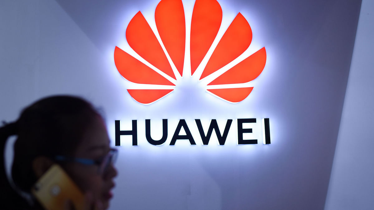 In this file photo taken on 8 July a woman uses her mobile phone in front of a Huawei logo at Beijing International Consumer Electronics Expo in Beijing. Photo: AFP