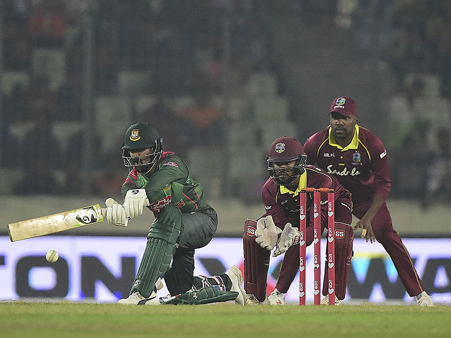 Bangladesh cricketer Liton Das (L) plays a shot as the West Indies cricketer Shai Hope (C) and Darren Bravo (R) looks on during the first One Day International (ODI) between Bangladesh and West Indies at the Sher-e-Bangla National Cricket Stadium in Dhaka on December 9, 2018. AFP