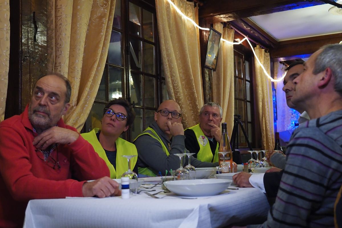 Yellow vest (gilets jaunes) protestors take notes as they watch French President Emmanuel Macron`s speech on TV on 10 December at a restaurant with French member of parliament Richard Damos, in Fay-au-Loges, near Orleans, Centre France. Photo: AFP