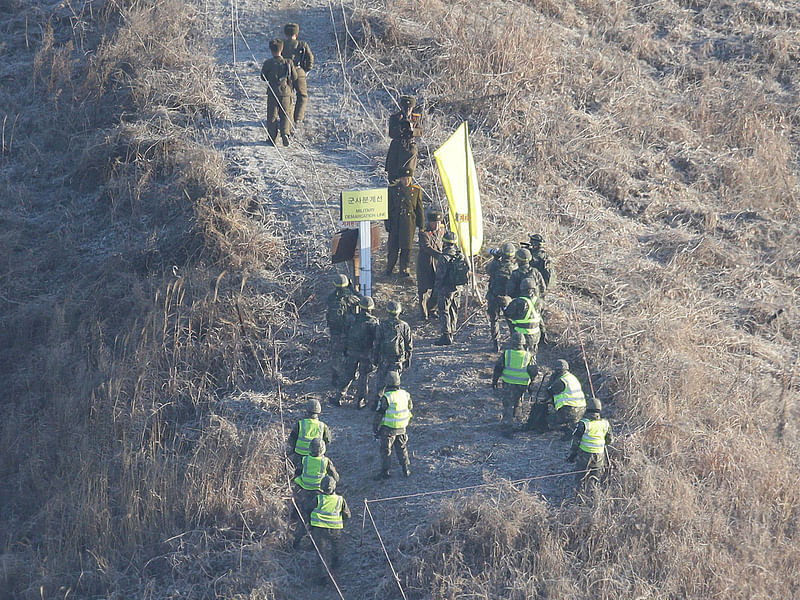 A South Korean army soldier, center bottom, shakes hands with a North Korean army soldier before crossing the Military Demarcation Line inside the Demilitarized Zone (DMZ) on 12 December. Photo: AFP