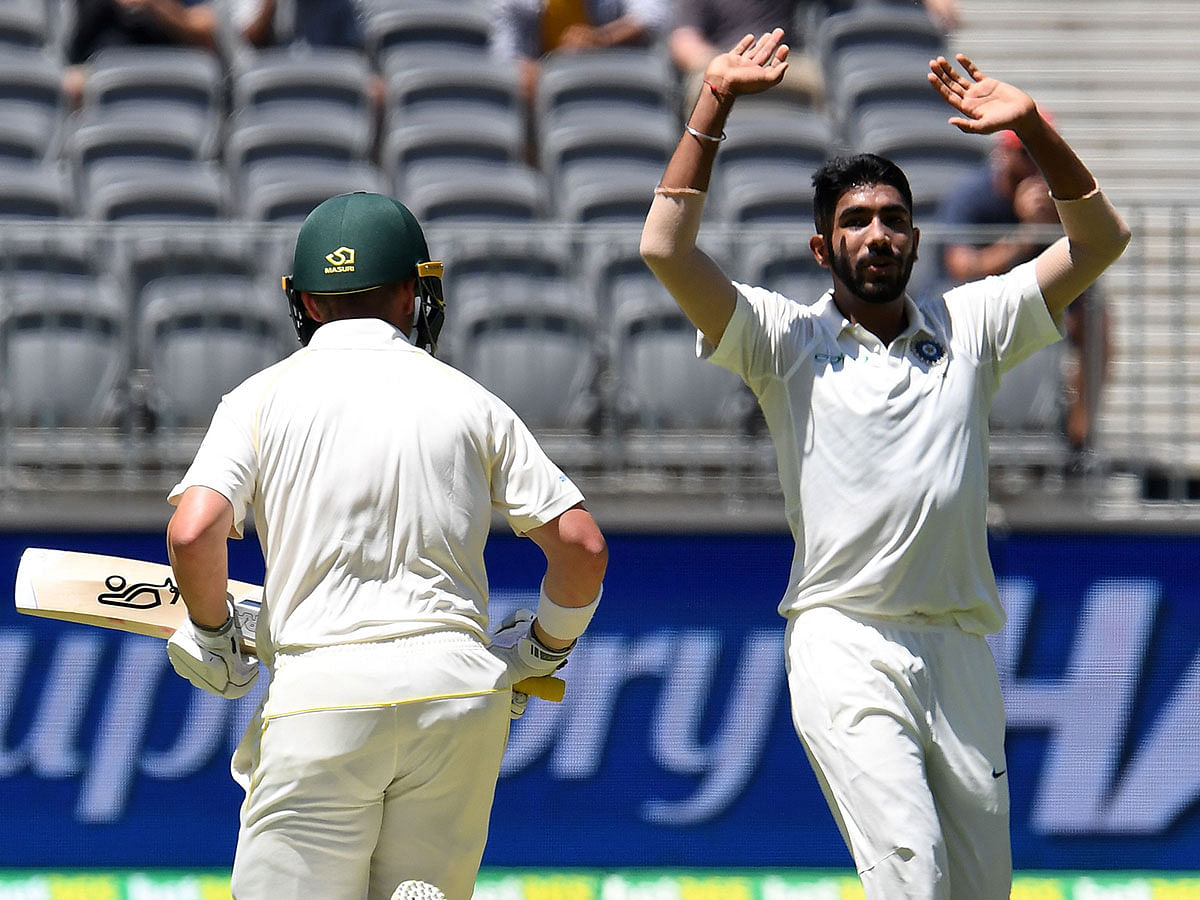 India`s paceman Jasprit Bumrah (R) reacts as Australia`s batsman Marcus Harris runs between the wickets on day one of the second Test cricket match between Australia and India in Perth on 14 December 2018. Photo: AFP