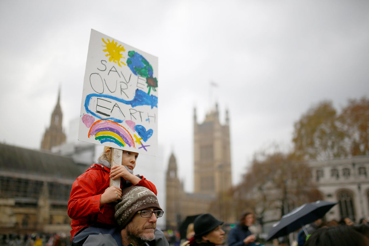 A demonstrator carries a child on his shoulders during a protest about the environment in Parliament Square, central London, Britain on 24 November. Photo: Reuters