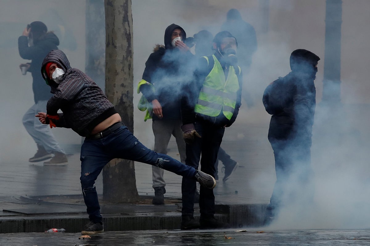 Protesters wearing yellow vests react as French police fire tear gas during a demonstration of the `yellow vests` movement in Paris, France, 15 December 2018. Photo: Reuters