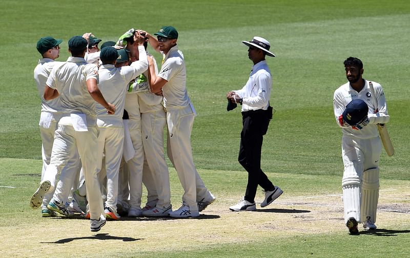 Australian players celebrate their victory as India`s last batsman Jasprit Bumrah (R) walks off the field during the day five of the second Test cricket match between Australia and India in Perth on 18 December. Photo: AFP