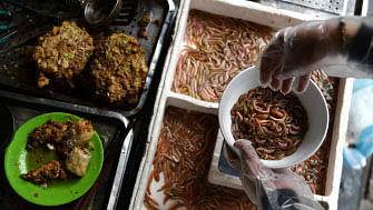 This photograph taken on 14 December 2018 shows Vietnamese woman Bui Thi Nga putting `cha ruoi` ragworms in a bowl to prepare patties at her stall in the old quarters of Hanoi. Photo: AFP