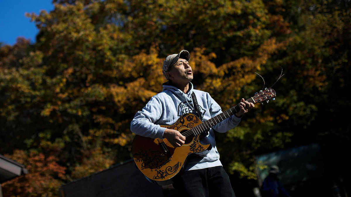 In this picture taken on 1 November 2018 Japanese musician Kyochi Watanabe plays his guitar as he poses for a photo at the entrance of Aokigahara Forest, known as Suicide Forest, in Narusawa village, Yamanashi prefecture. Photo: AFP