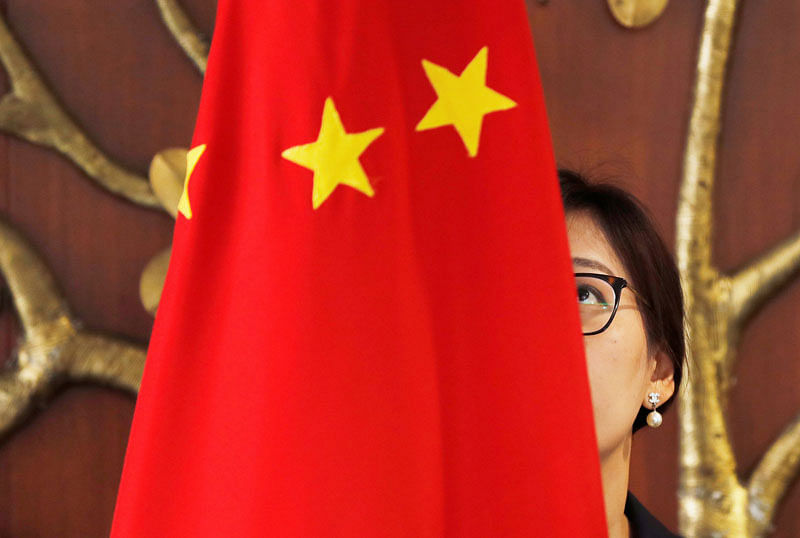 A Chinese official adjusts a Chinese flag before the start of a meeting between foreign minister Wang Yi and Indian foreign minister Sushma Swaraj in New Delhi, India, on 21 December 2018. Reuters File Photo