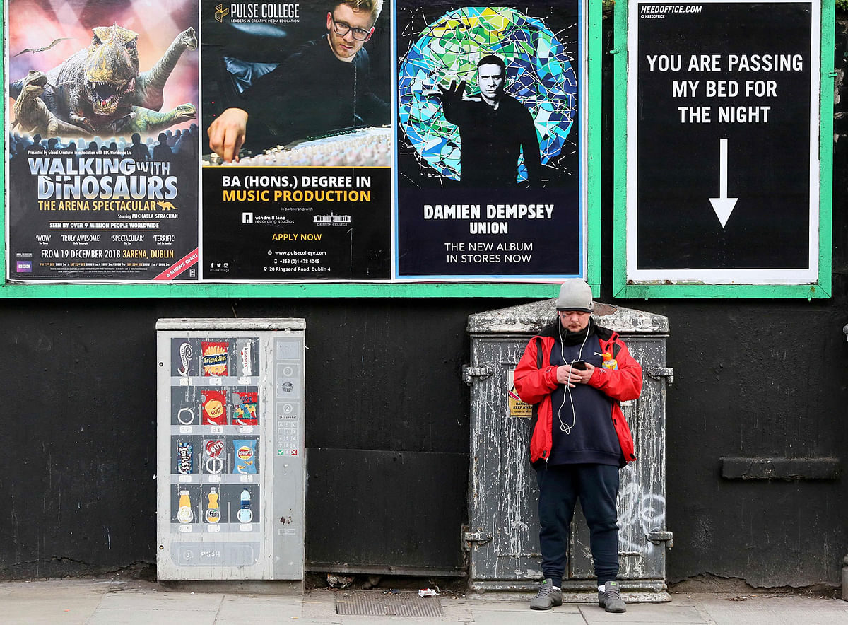 A man stands underneath a poster pointing out the space for a homeless person, amongst advertising posters in Dublin City centre on 10 December 2018. Photo: AFP