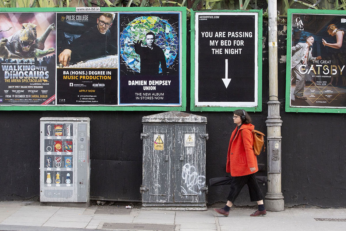 A woman walks past a poster pointing out the space for a homeless person, amongst advertising posters in Dublin City centre on 10 December 2018. Photo: AFP