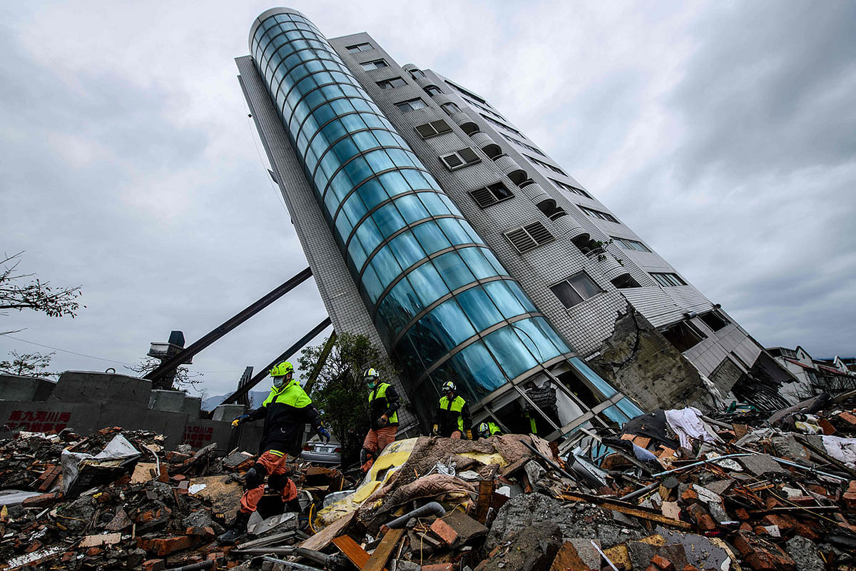 Rescue workers (bottom L) walk out from the Yun Tsui building, which is leaning at a precarious angle, in the Taiwanese city of Hualien on 8 February 2018 after the city was hit by a 6.4-magnitude quake late on 6 February. Photo: AFP