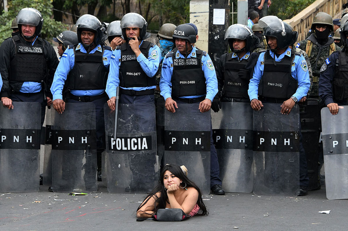 A supporter of the presidential candidate for the Honduran Opposition Alliance Against the Dictatorship for the past election, Salvador Nasralla, lies on the street in front of police officers during a demonstration against the contested re-election of President Juan Orlando Hernandez, in Tegucigalpa on 21 January 2018. Photo: AFP