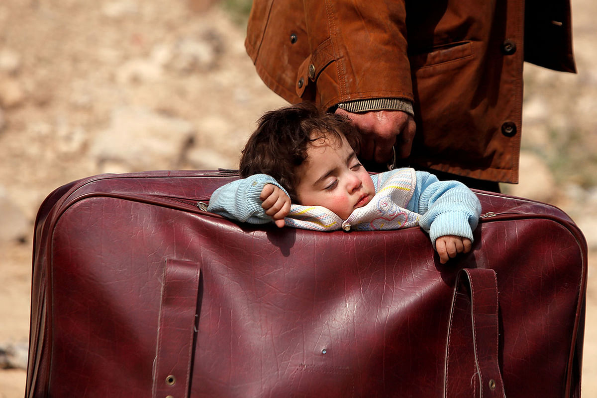 A child sleeps in a bag in the village of Beit Sawa, eastern Ghouta, Syria, 15 March 2018. Photo: Reuters