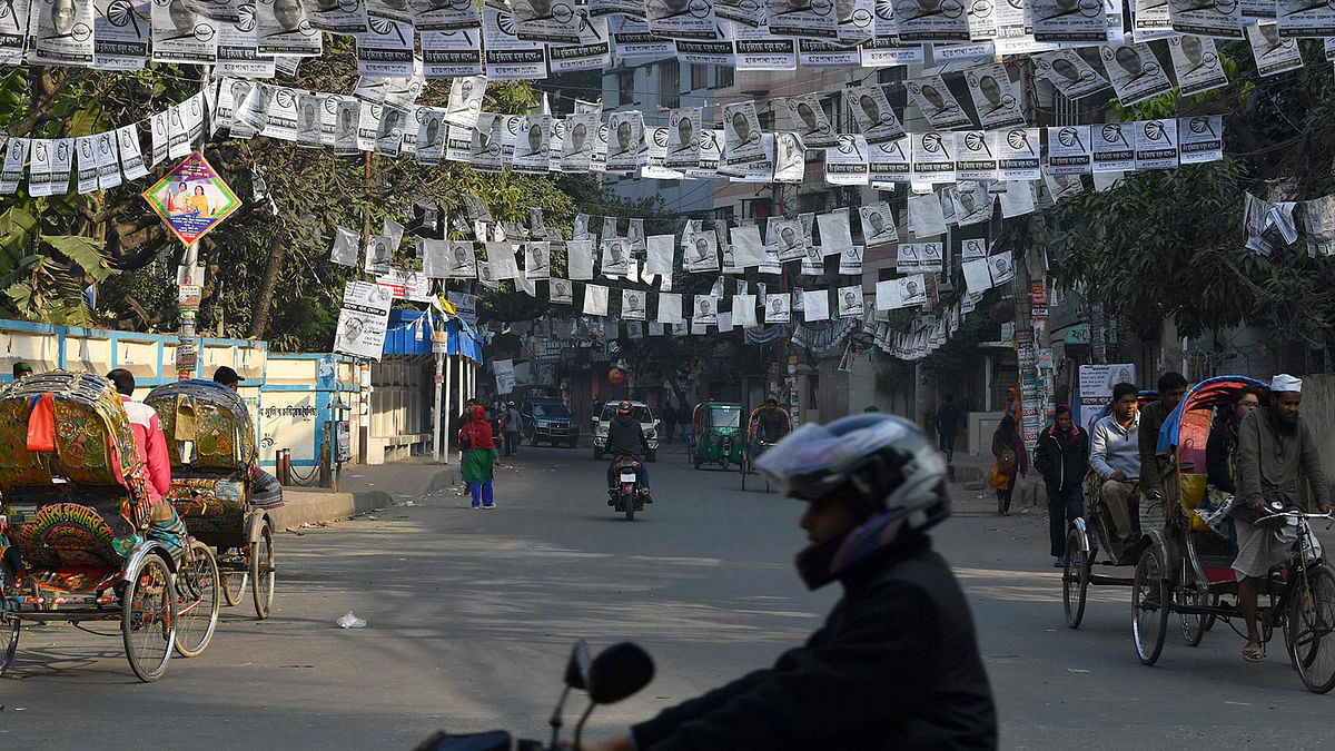 People go about a street adorned with election posters in Dhaka on 28 December, 2018, ahead of the 30 December general election. Photo: AFP