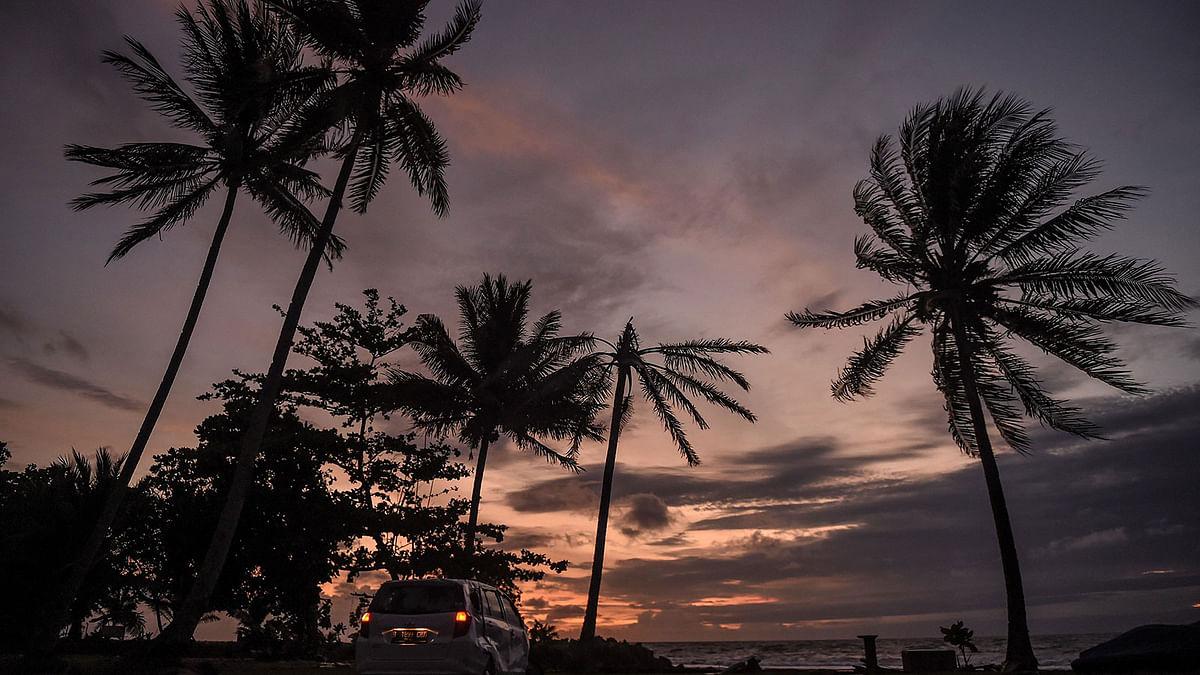 A damaged car with the lights still on is seen near a villa during sunset in Pandeglang in Banten province on 28 December, 2018, following the 22 December tsunami that was caused by activity at a volcano known as the `child` of Krakatoa. Photo: AFP