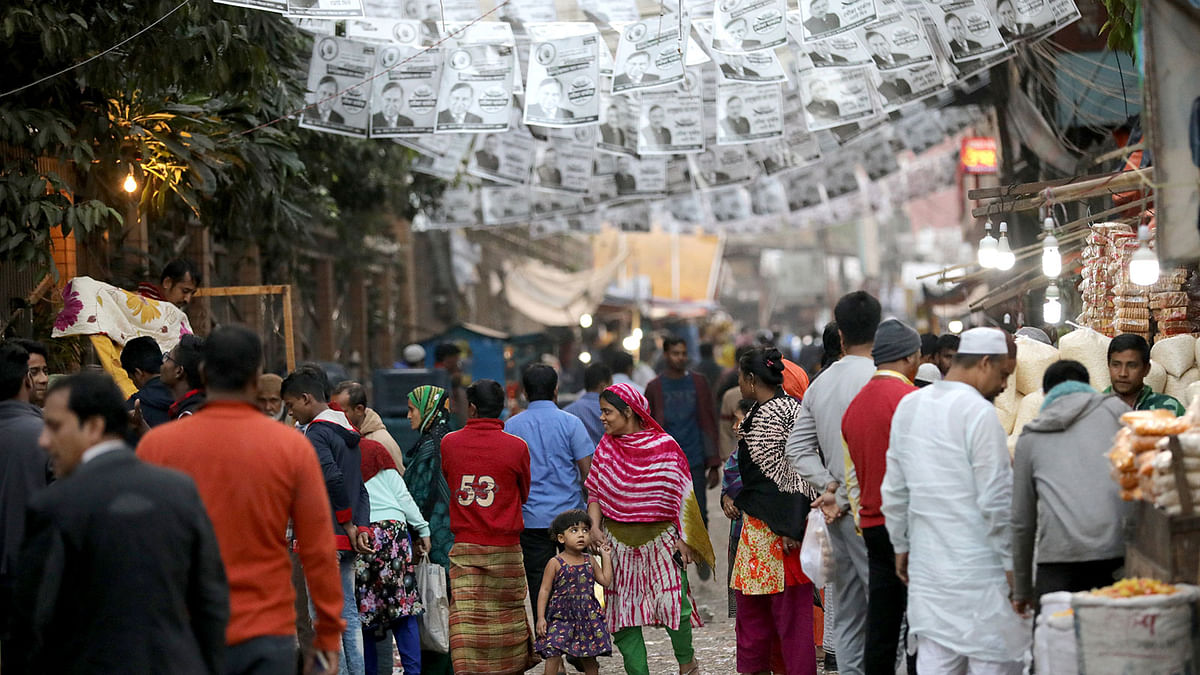 People walk below posters of an election candidate ahead of the 11th general election in Dhaka, Bangladesh, 28 December 2018. Photo: Reuters