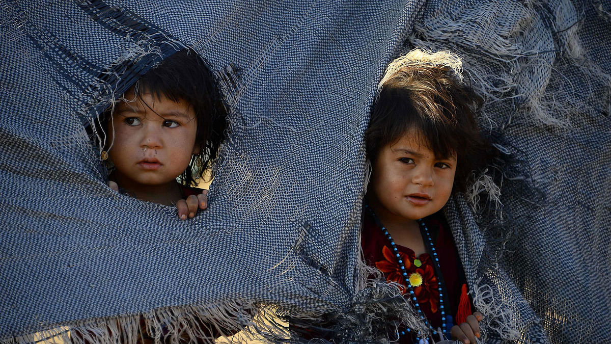 In this file photo taken on 5 August 2018, drought-displaced Afghan children look out from their tent at a camp for internally displaced people in the Injil district of Herat province. Photo: AFP