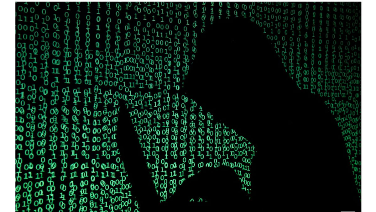 A hooded man holds a laptop computer as cyber code is projected on him in this illustration picture taken on 13 May 2017. -- Photo: Reuters