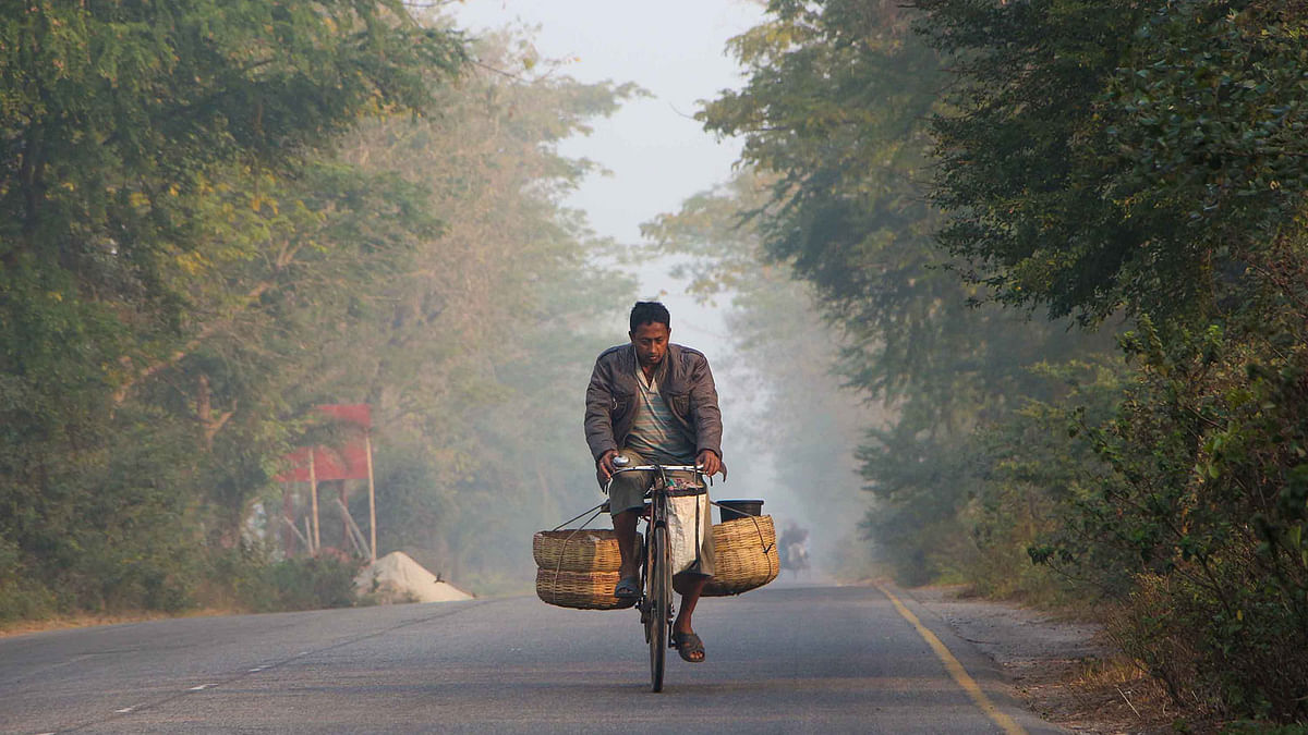A man pedals his bicycle in the winter morning along the road at Deyana, Khulna. Photo: Saddam Hossain