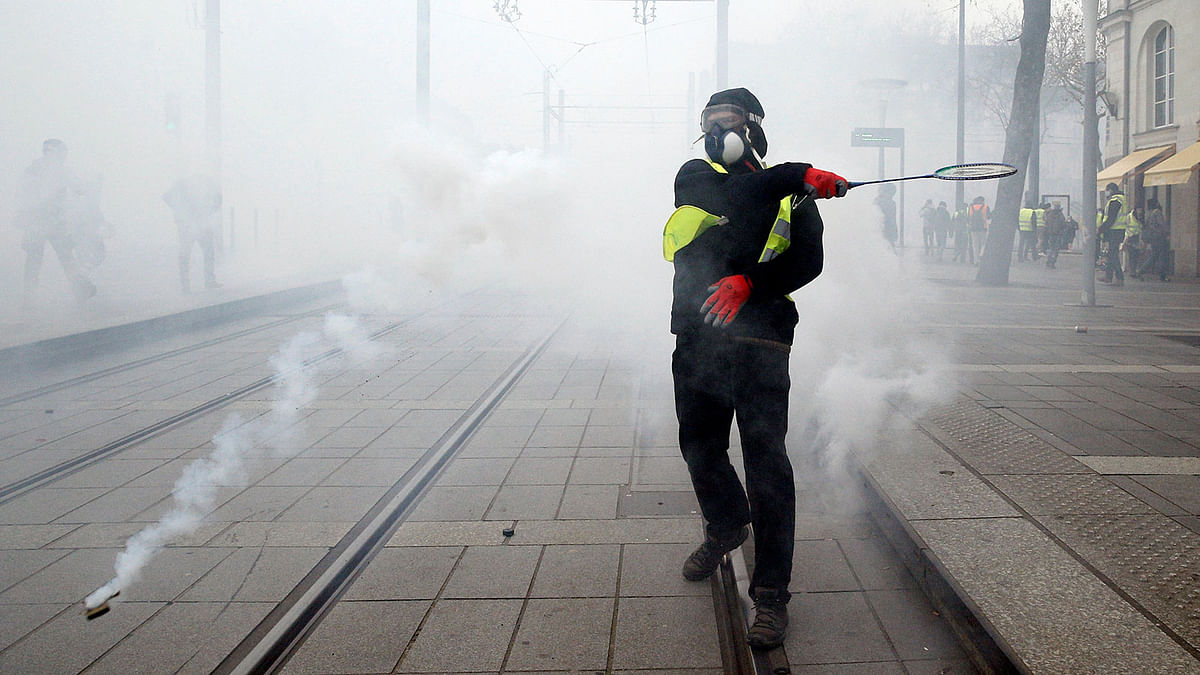A protester returns a tear gas canister fired by police during a demonstration of the `yellow vests` movement in Nantes, France, on 5 January 2019. Photo: Reuters