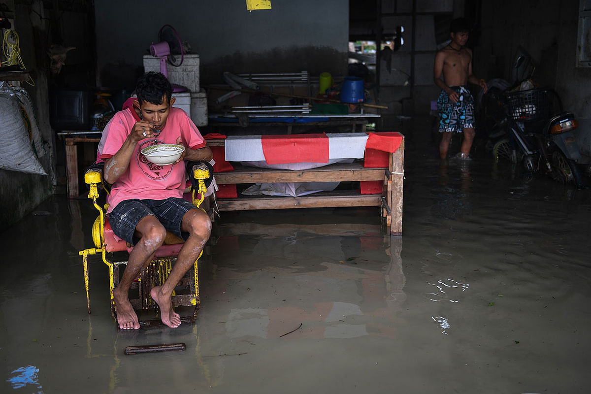 A man eats in his flooded home in the aftermath of tropical storm Pabuk in the southern Thai province of Nakhon Si Thammarat on 5 January 2019. Photo: AFP