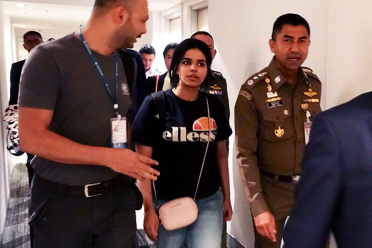 This handout picture taken and released by the Thai Immigration Bureau on 7 January 2019 shows 18-year-old Saudi woman Rahaf Mohammed al-Qanun (C) being escorted by a Thai immigration officer (R) and United Nations High Commissioner for Refugees (UNHCR) officials at Suvarnabhumi international airport in Bangkok. Photo: AFP