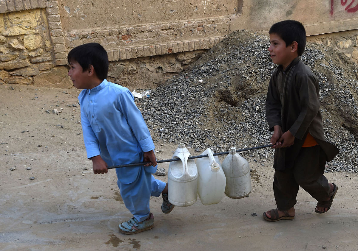 This photo taken on 25 October 2018 shows Afghan boys carrying containers of water to their home in Kabul. Photo: AFP
