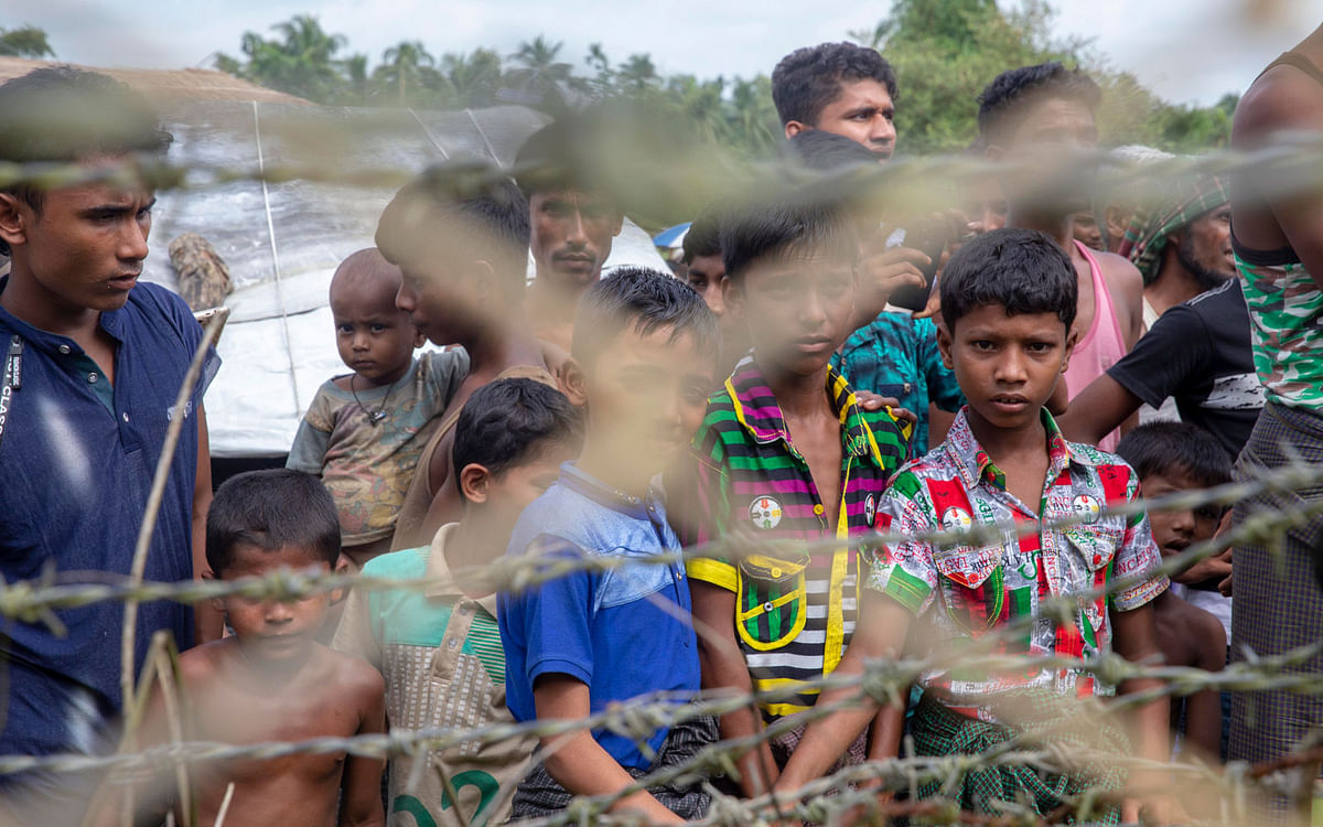 Rohingya refugees gather near the fence in the “no man’s land” zone between Myanmar and Bangladesh border as seen from Maungdaw, Rakhine state on 24 August, 2018. Photo: AFP