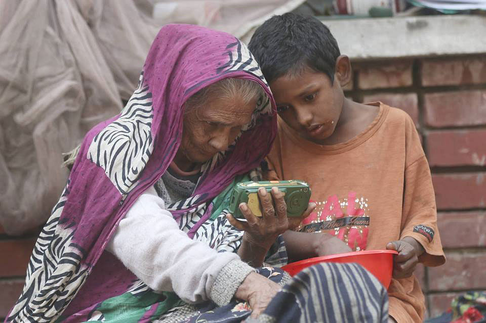 A 70-year-old woman watching a movie on a cellular phone with her grandson in front of Curzon Hall, Dhaka University, on 13 January. Photo: Abdus Salam