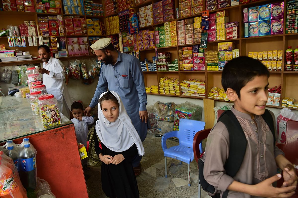 In this picture taken on 29 September 2018 Afghan refugee Ashiqullah Jan visits a shop with his children in Peshawar. Photo: AFP