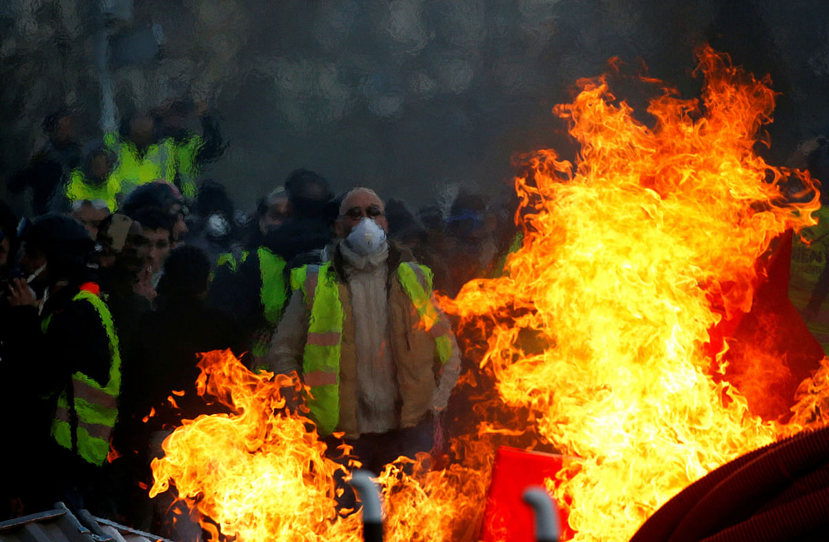 Protesters wearing yellow vests are seen behind a fire as they attend a demonstration of the `yellow vests` movement in Angers, France, on 19 January 2019. Photo: Reuters